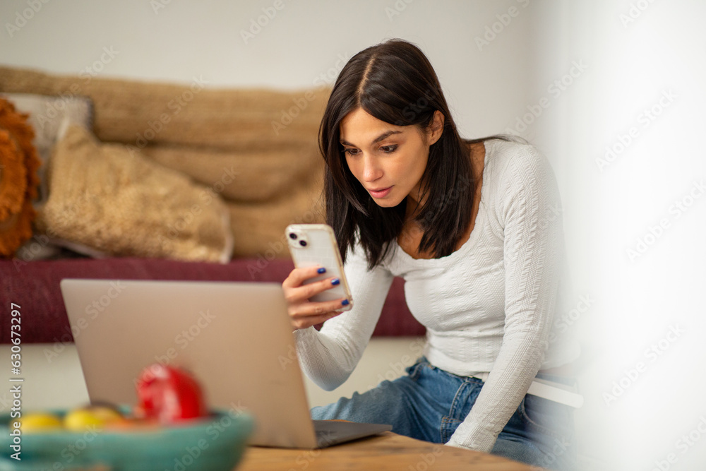 woman sitting at home with laptop and mobile phone woman sitting at home with laptop and mobile phone