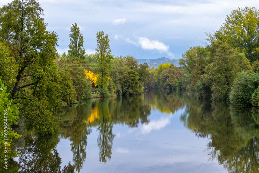 Beautiful landscape of trees on the banks of the Jerte river as it passes through Plasencia, with the mountains of Valle del Jerte in the background.Beautiful nature scenery in Extremadura, Spain Beautiful landscape of trees on the banks of the Jerte river as it passes through Plasencia, with the mountains of Valle del Jerte in the background.Beautiful nature scenery in Extremadura, Spain