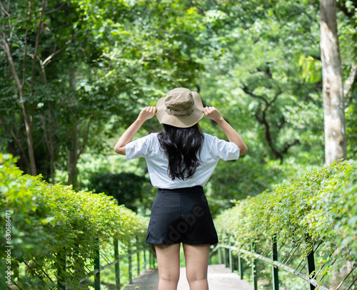 Young woman with hat hiking in forest during summer season, solo traveler walking in the forest. © Kunlathida