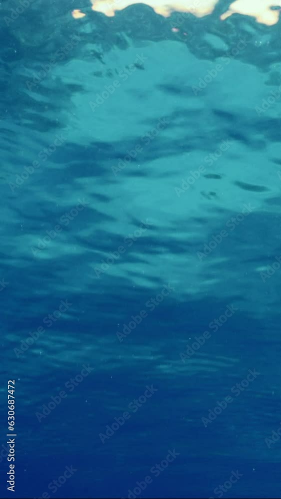 Vertical video, Surface of water during calm on bright sunny day, Slow motion. Underwater view of calm blue water surface. Small swell on surface of Ocean.Beautiful clear blue water surface Vertical video, Surface of water during calm on bright sunny day, Slow motion. Underwater view of calm blue water surface. Small swell on surface of Ocean.Beautiful clear blue water surface
