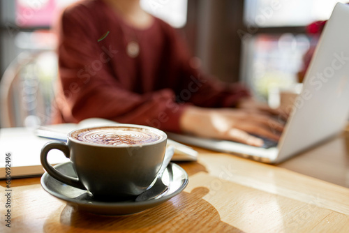 coffee on table of person working remotely on her laptop at a cafe photo