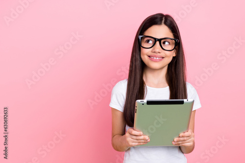 Photo portrait of cute schoolgirl hold ebook reading look empty space wear trendy white outfit isolated on pink color background