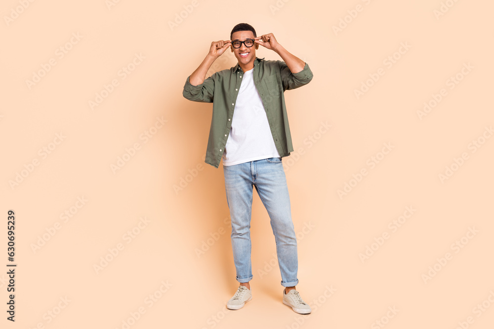 Full size photo of satisfied glad young person hands touch eyeglasses good mood isolated on beige color background Full size photo of satisfied glad young person hands touch eyeglasses good mood isolated on beige color background