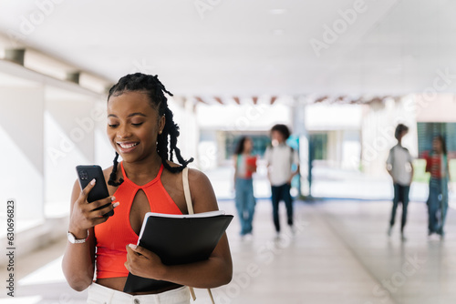 Portrait of an African female student on a university campus using her mobile phone.