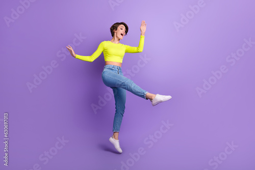 Fototapeta Naklejka Na Ścianę i Meble -  Full body portrait of carefree energetic lady jumping dancing empty space ad isolated on purple color background