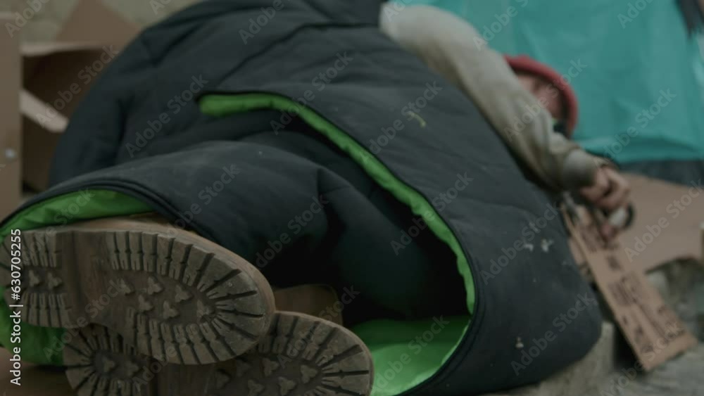 Medium close up of body of homeless man laying covered with old blanlet on street Medium close up of body of homeless man laying covered with old blanlet on street