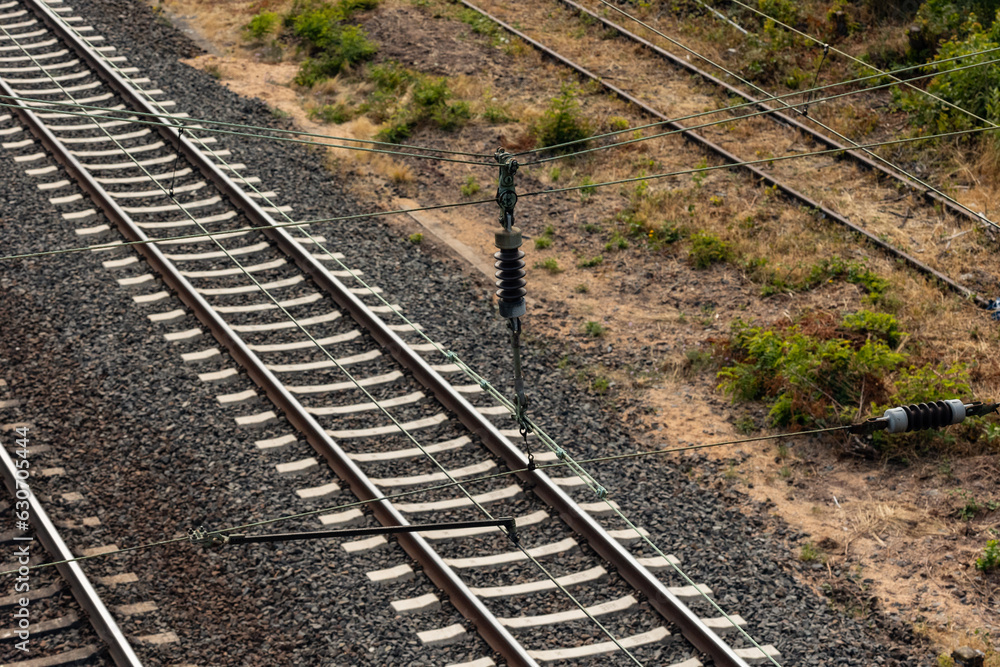 Obraz premium Contact wire, insulator and railroad tracks. Technology, railroad ties and transportation.