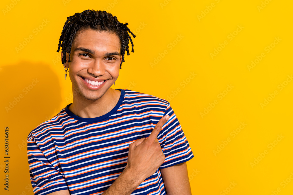 Photo of attractive cool guy wear stylish clothes finger direct empty space recommend black friday sale isolated on yellow color background Photo of attractive cool guy wear stylish clothes finger direct empty space recommend black friday sale isolated on yellow color background