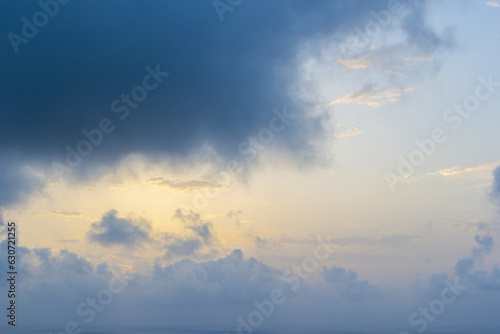 Clouds in the blue sky at sunrise in Costa Blanca, Alicante, Spain. Sunlight shines through large cumulus clouds. The morning sun rays over the wavy blue sea