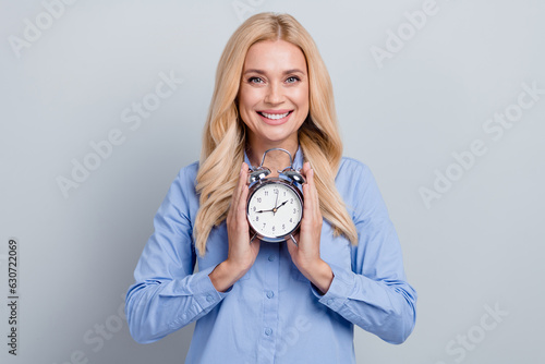 Portrait of cheerful gorgeous lady beaming smile hands hold retro bell ring clock isolated on grey color background