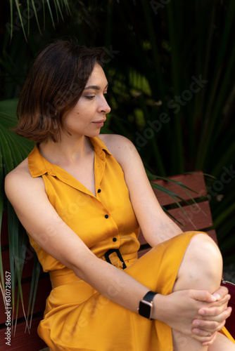 Attractive woman in yellow dress sitting