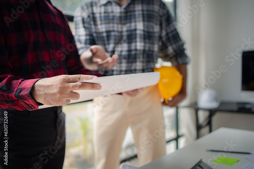 The home design architects are reviewing the house plan draft, the project commissioned by the client, and the custom design before delivery. Interior design and decoration ideas.