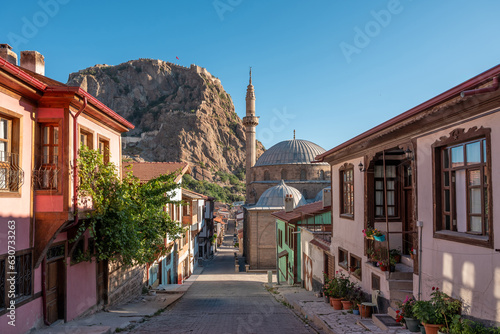 Traditional Turkish Ottoman houses in Afyonkarahisar Turkey. Afyon Castle on the rock and Mevlevihane Museum in front of it photo