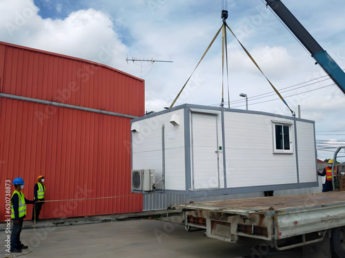 The Crane trucks transport the mobile office buildings or container site office for installation in the construction site area, project mobilization.