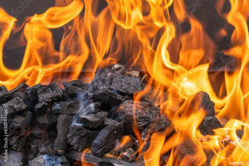 the charcoals are lit by a hot flame in a barbecue