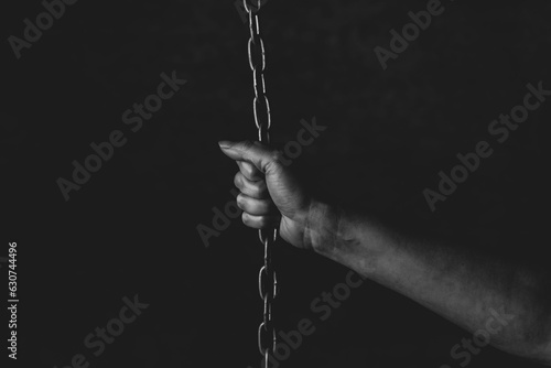 Canvas Print Hand of a person chained on black background, feeling a lack of freedom, prison