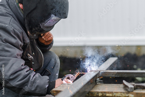 Shielded metal arc welding. Worker welding metal with electrodes, wearing protective helmet and gloves. Close up of electrode welding and electric sparks