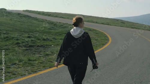 A beautiful Ukrainian young woman traveler walks along the most beautiful high mountain road in Romania Transalpina highway at cold dayt. Transalpina, Carpathian mountains in Romania at day. Slow photo