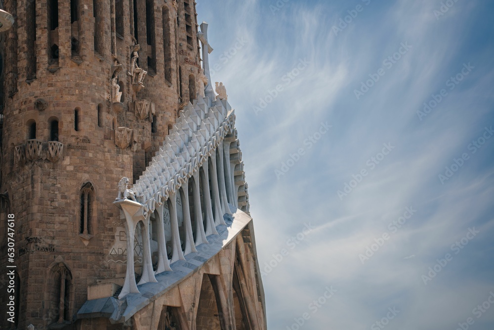 Obraz premium Low angle shot of Sagrada Familia under a blue sky and sunlight in Barcelona, Spain