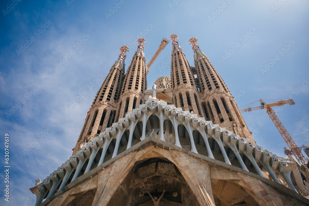 Low angle shot of Sagrada Familia under a blue sky and sunlight in Barcelona, Spain