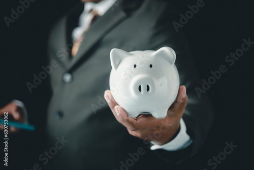 Businessman holding white medium pig piggy bank To save money, bank deposit of savings business investment concept 