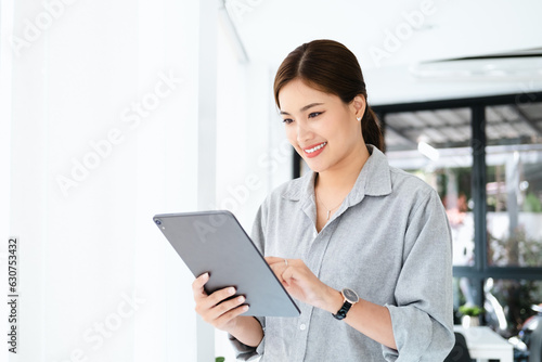 Young Asian businesswoman is happy to work at the modern office using a tablet. copy space