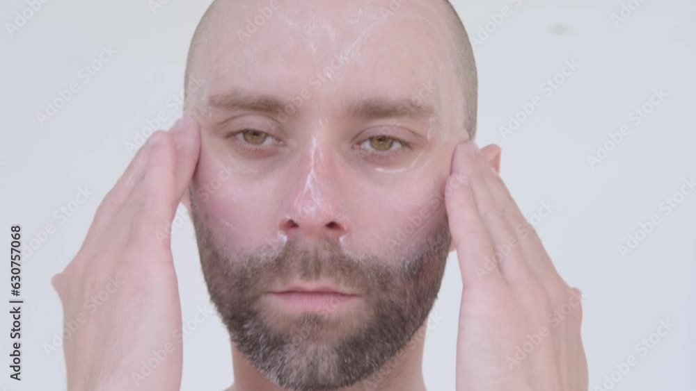 closeup of charismatic bearded young man 30 years old applies cream to