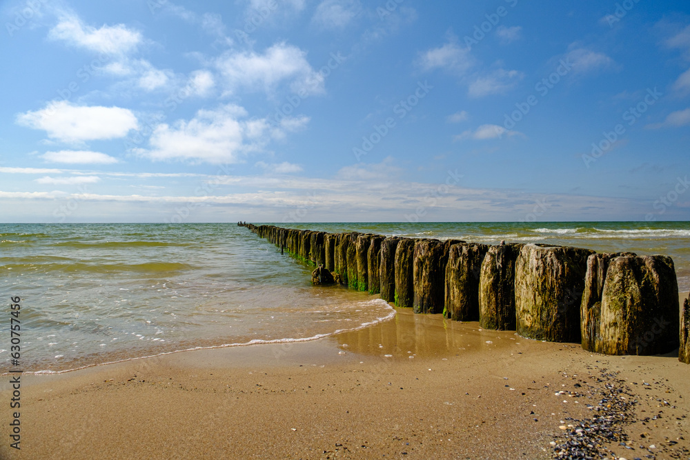 Side view of an old wooden pier on a large bay with blue sky in the background. Baltic Sea Latvia