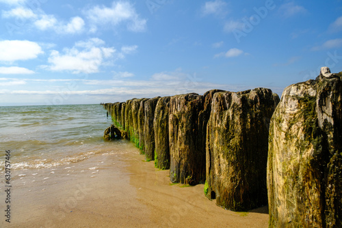 Side view of an old wooden pier on a large bay with blue sky in the background. Baltic Sea Latvia