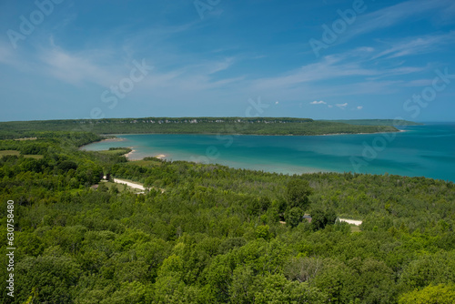 Aerial panoramic view of crystal clear turquoise Georgian Bay water and sandy beaches with lush green forest around it. Beautiful summer day, clear blue sky. Bruce peninsula, Ontario, Canada.
