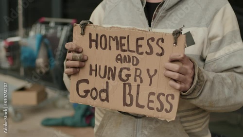 Cropped shot of male tramp standing with sign homeless and hungry outside on street
