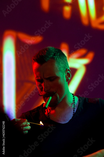Focused man lighting cigar with match in nightclub