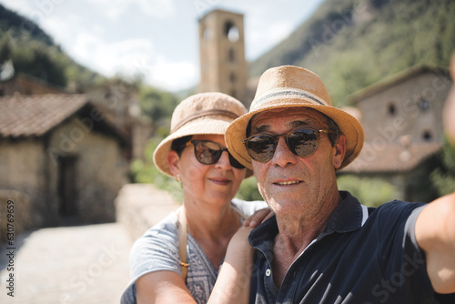 Older couple taking selfie with smartphone outside - Two elderly tourists enjoying summer vacation together in Beget village, Girona, Catalonia - Lifestyle concept with mature woman and man smiling at © Fotografia Juan Reig