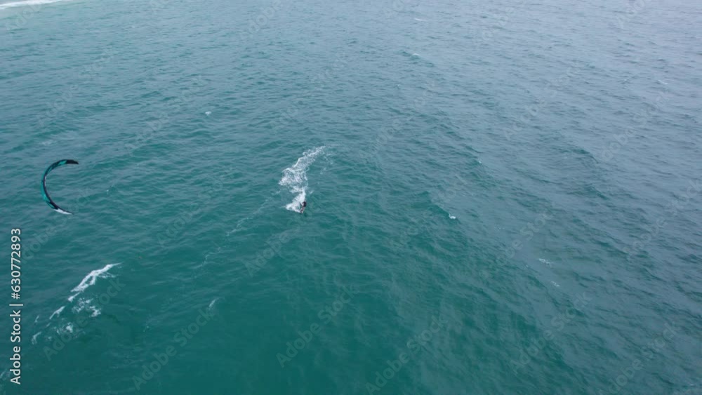 A guy rides on the waves of the ocean on kitesurfing. Green transparent water. Yellow sand. Top view from a drone to a paraglider. The board slides on the water. The big green island of Phuket A guy rides on the waves of the ocean on kitesurfing. Green transparent water. Yellow sand. Top view from a drone to a paraglider. The board slides on the water. The big green island of Phuket
