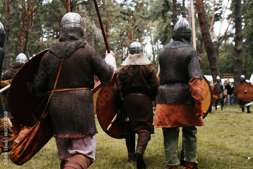Back view of attacking medieval warriors in the forest.