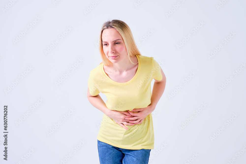 young blonde girl with stomach ache or intestinal discomfort in yellow t-shirt on white background young blonde girl with stomach ache or intestinal discomfort in yellow t-shirt on white background
