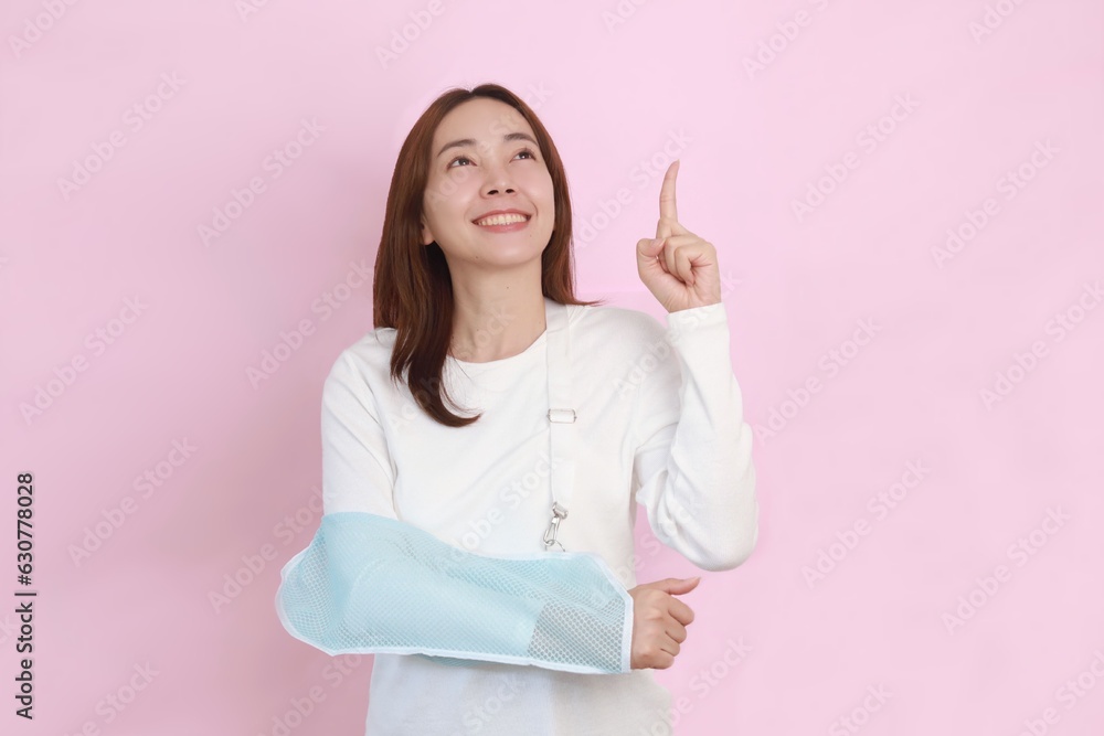 Patient with broken arm in sling, Asian woman in casual white shirt broken hand wearing an arm brace standing over pink background with copy space.
Patient with broken arm in sling, Asian woman in casual white shirt broken hand wearing an arm brace standing over pink background with copy space.
