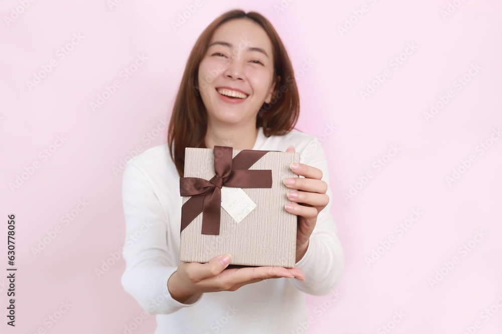 Cheerful Asian woman holding a gift box standing over pink background,copy space. Cheerful Asian woman holding a gift box standing over pink background,copy space.