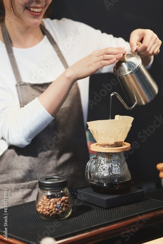 Cheerful woman making a coffee cup in cafe,Barista holding a cup of hot coffee for the first Morning.