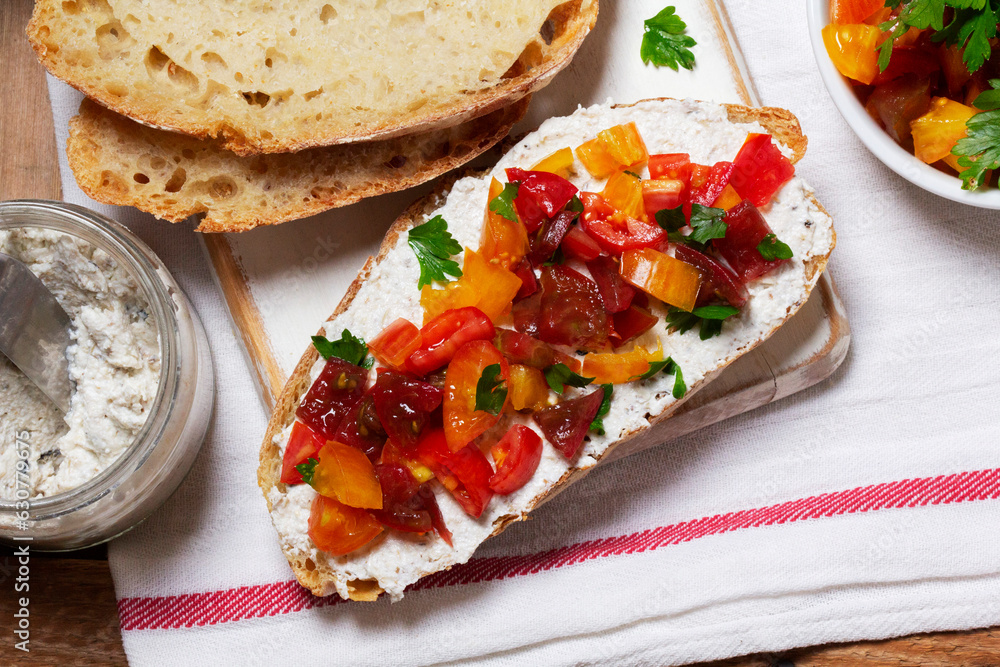 Bruschetta from homemade bread with cottage cheese and sprat pate and tomatoes on a wooden background. Rustic style.