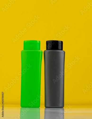 Clear plastic bottles, one green and one black, set against a bright yellow background