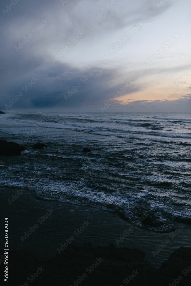 Obraz premium Moody sunset photo of the ocean from the Pacific Coast Highway with rich blue and purple colors.
