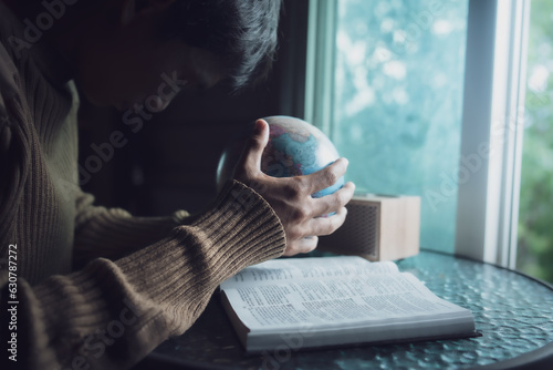 Man praying for globe and people around the world with bible in every morning.