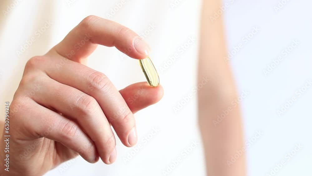 Medicine capsule in female hands, Omega-3. Bright yellow transparent vitamins on a white background. Medicine and healthcare. Vitamins and dietary supplements. Omega 3 Gold Fish Oil Capsule Medicine capsule in female hands, Omega-3. Bright yellow transparent vitamins on a white background. Medicine and healthcare. Vitamins and dietary supplements. Omega 3 Gold Fish Oil Capsule