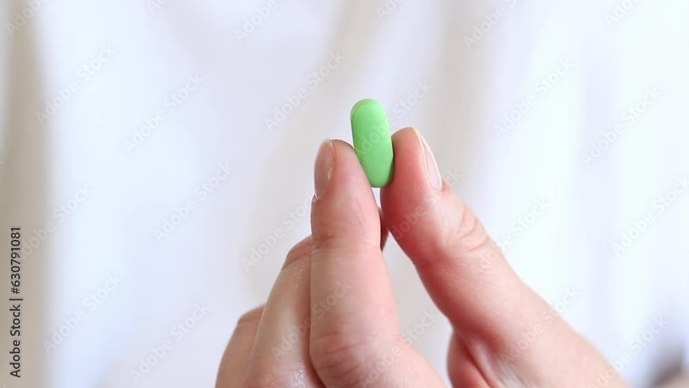 Vitamins on a white background. The hand holds one green pill with two fingers. The concept of medicine and health. Vitamins and dietary supplements Vitamins on a white background. The hand holds one green pill with two fingers. The concept of medicine and health. Vitamins and dietary supplements