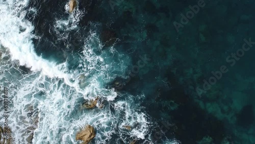 Aerial video of the rocky mountains on the shore and the sea on a sunny day
