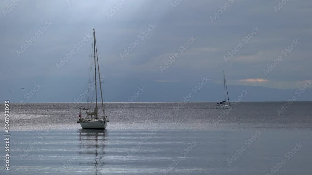 Sailboats in the sea with a cloudy sky in the background Sailboats in the sea with a cloudy sky in the background