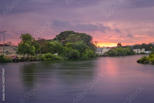Calm pink sunset over a rural village on the river with moored boats