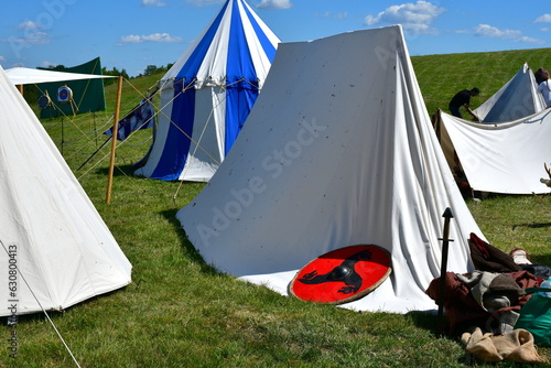 A close up on a medieval camp full of targes, shields, cloth tents, weaponry, and utensils for cooking food for soldiers seen during a historical fair or festival in Poland in summer
