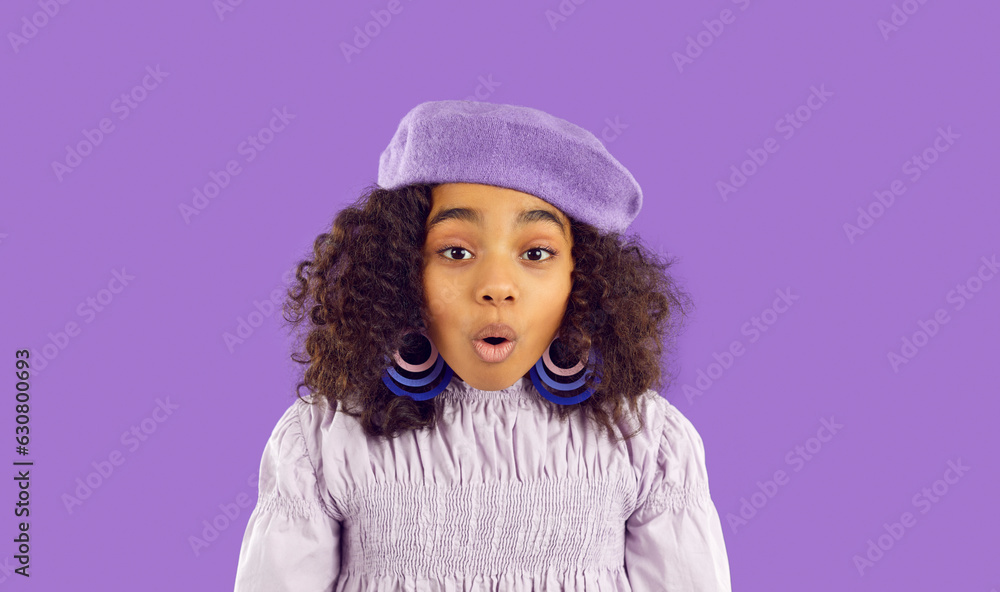 Black kid model amazed by something. Cute little child in trendy modern outfit says WOW COOL. Black girl in purple French beret and hoop earrings looking at camera with surprised happy face expression Black kid model amazed by something. Cute little child in trendy modern outfit says WOW COOL. Black girl in purple French beret and hoop earrings looking at camera with surprised happy face expression